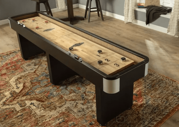 A Brunswick Shuffleboard on a rug in a living room.
