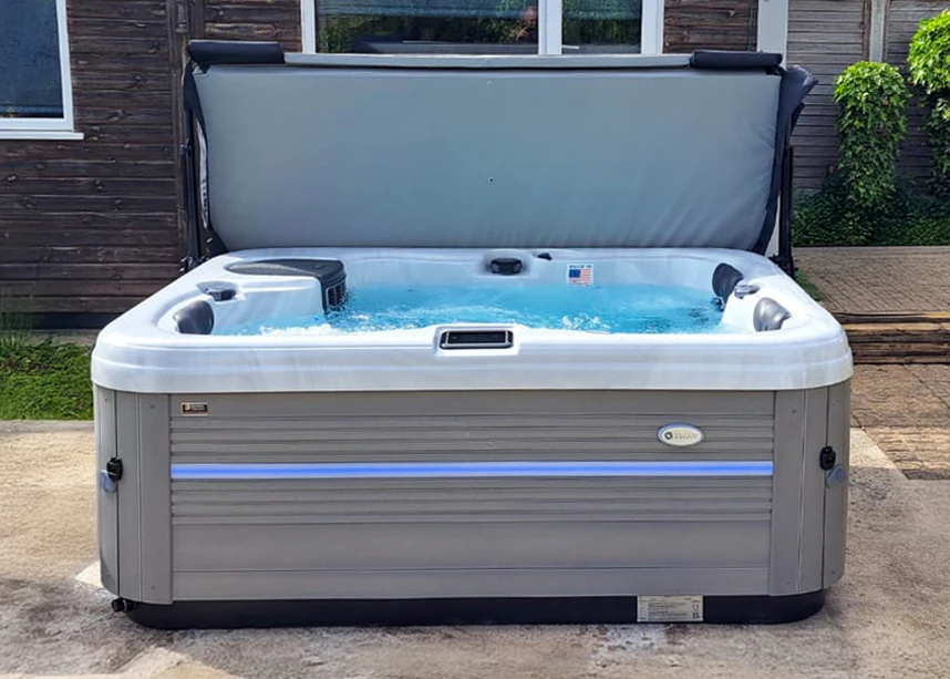 grey hot tub with white acrylic shell and open cover, sat on a patio