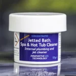 The front of a 57g tub of Ahh-Some Jetted bath, spa & hot tub cleaner on the edge of a hot tub