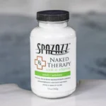 The front of a 19oz tub of Spazazz naked therapy hot tub aromatherapy crystals on the edge of a hot tub
