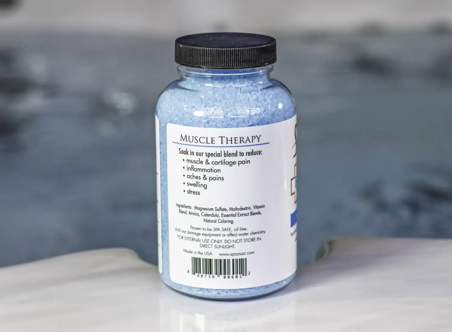 The left of a 19oz bottle of Spazazz muscle Therapy on the side of a hot tub