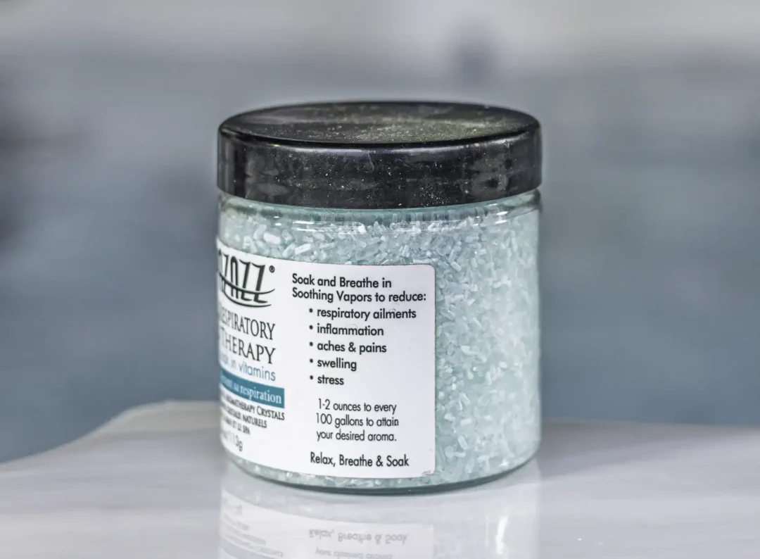 The right of a 4oz bottle of Spazazz respiratory Therapy hot tub aromatherapy crystals on the side of a hot tub