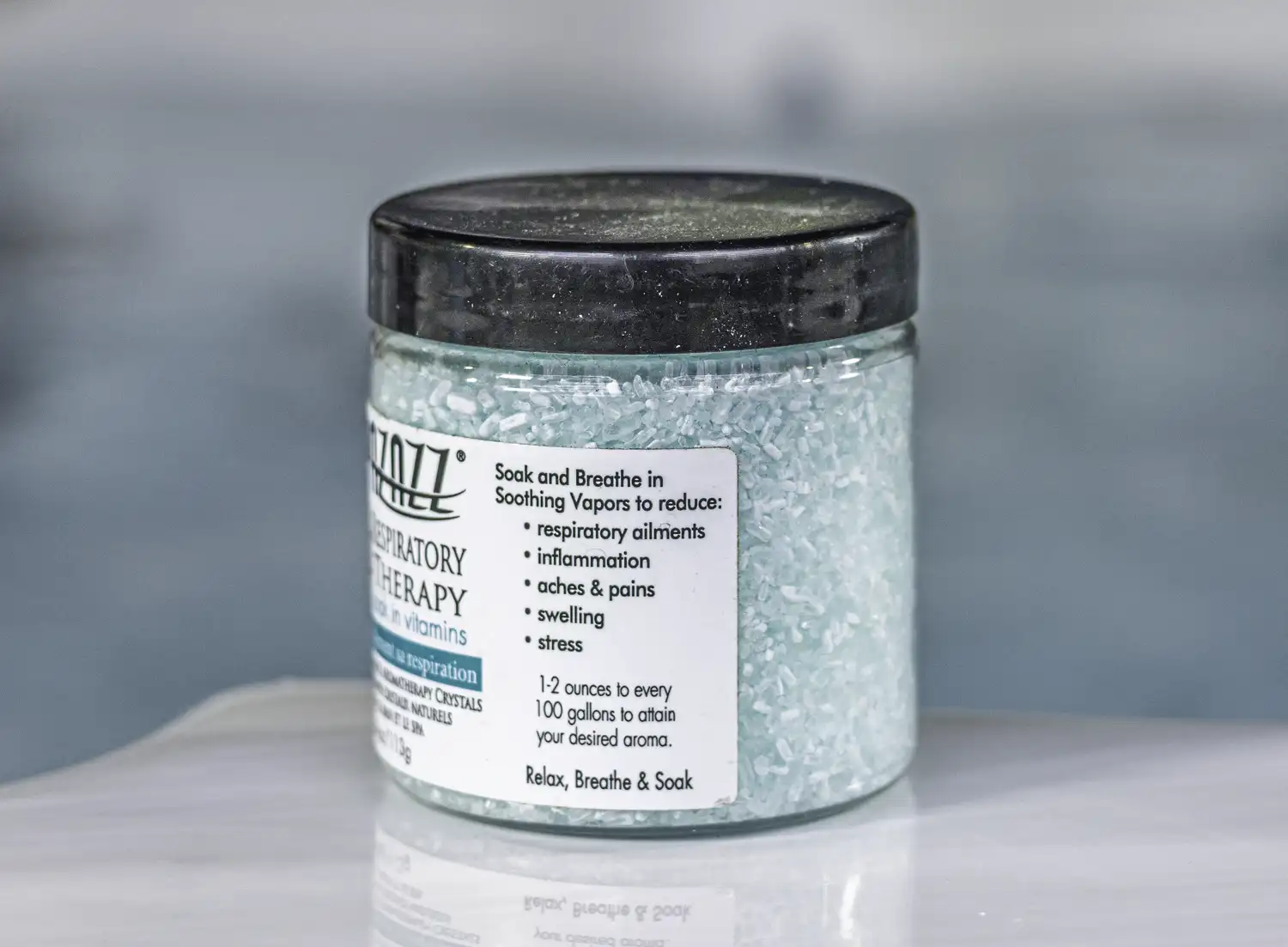 The right of a 4oz bottle of Spazazz respiratory Therapy hot tub aromatherapy crystals on the side of a hot tub
