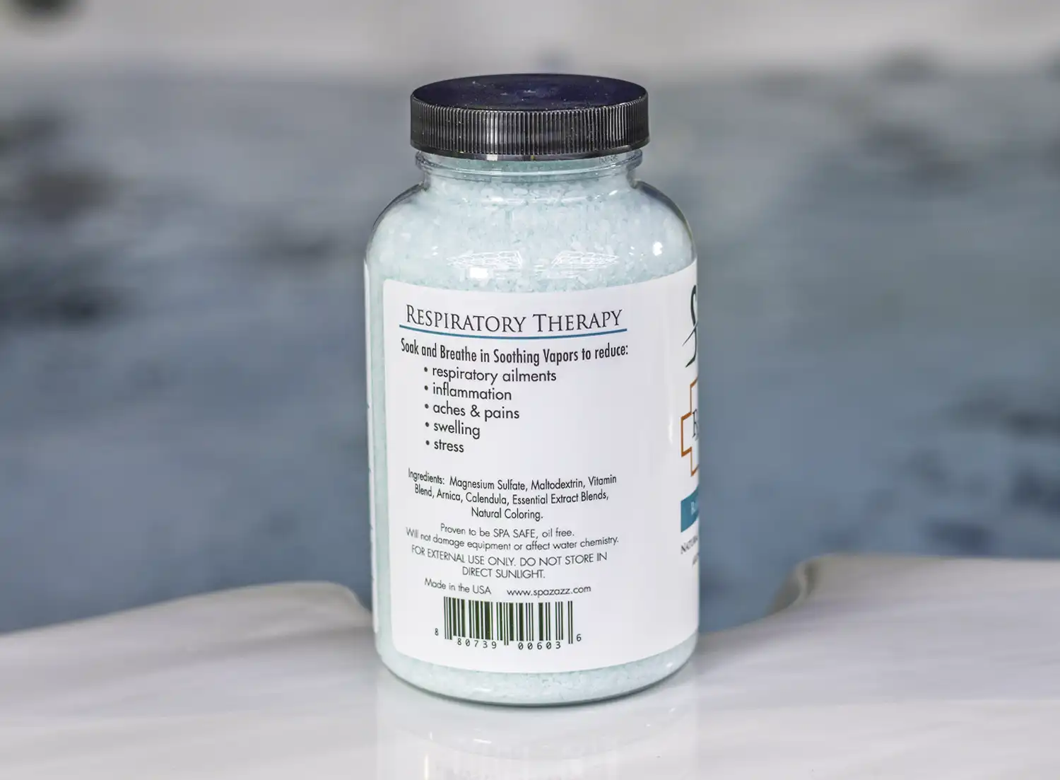 The left of a 19oz bottle of Spazazz respiratory Therapy on the side of a hot tub
