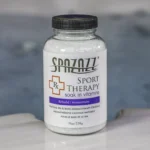 The front of a 19oz bottle of Spazazz sport Therapy hot tub aromatherapy crystals on the side of a hot tub