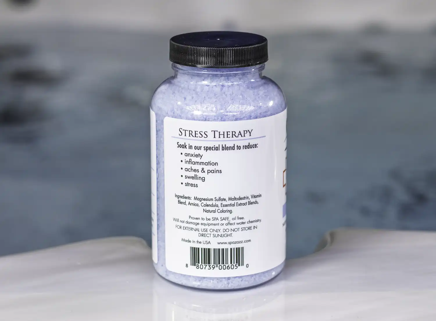 A 19oz bottle of Spazazz Stress Therapy on the side of a hot tub