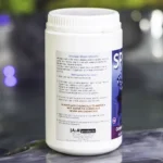 The left side of a 1kg tub of Splash granular shock chlorine on the edge of a hot tub