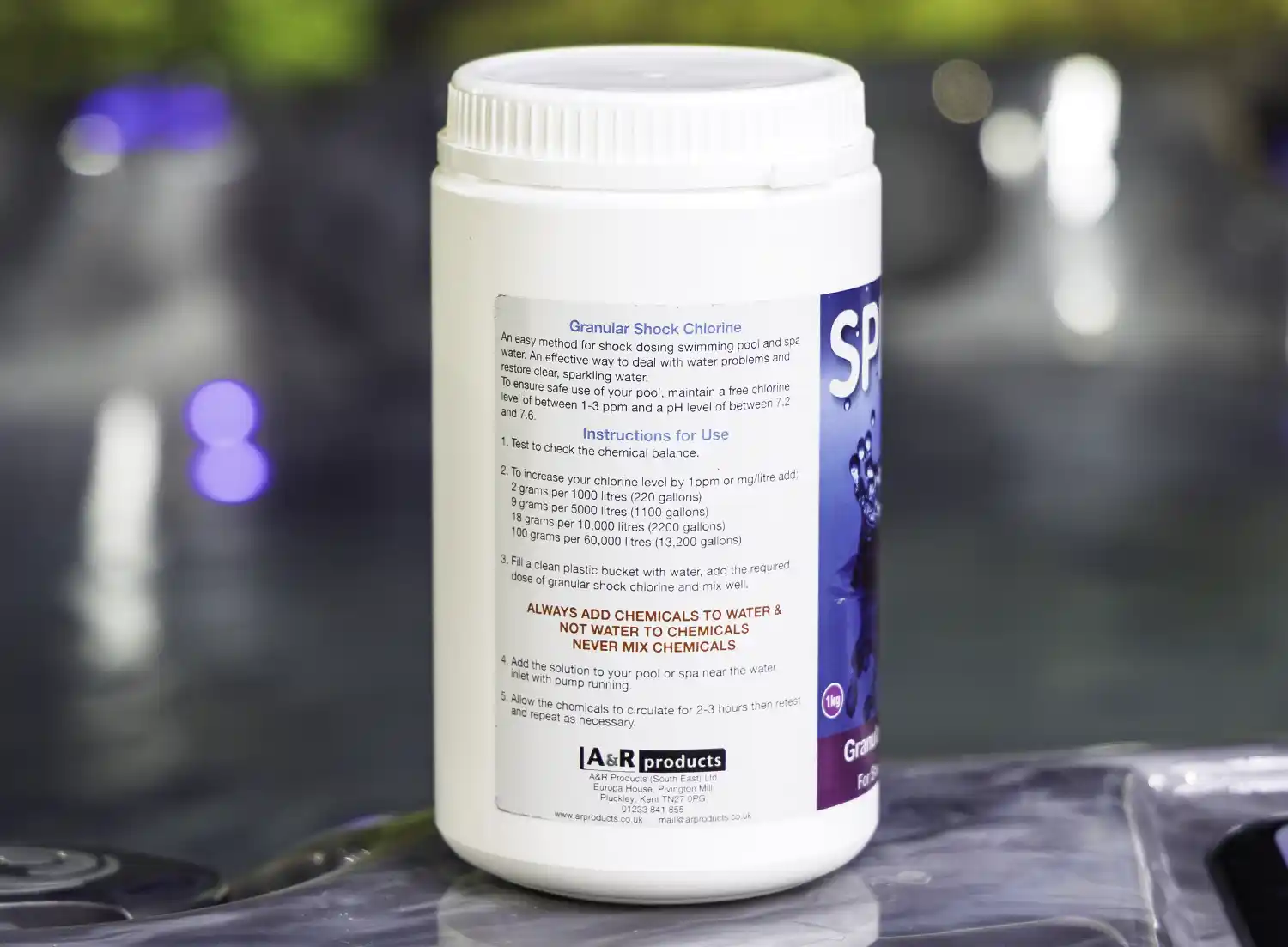 The left side of a 1kg tub of Splash granular shock chlorine on the edge of a hot tub