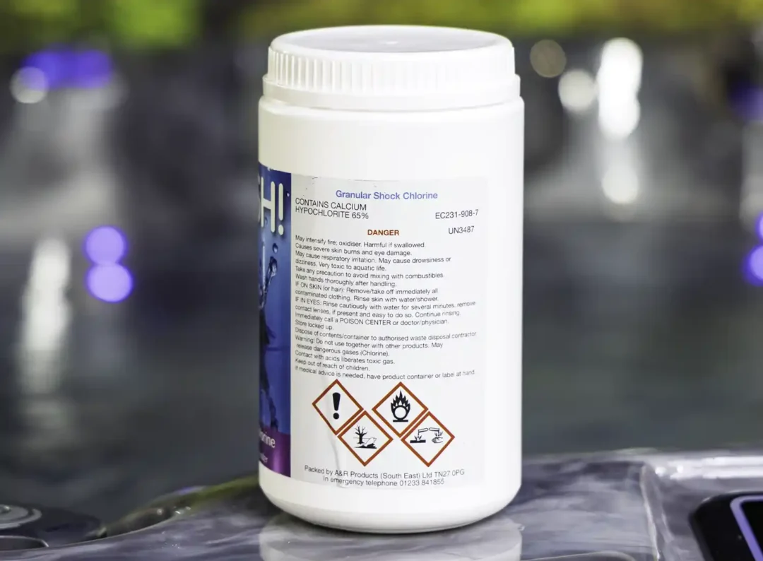 The right side of a 1kg tub of Splash granular shock chlorine on the edge of a hot tub