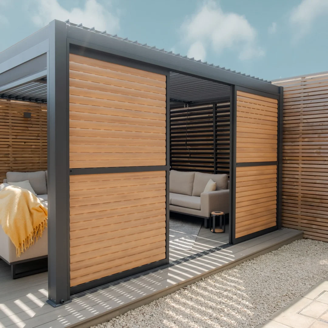 Maze Living Como pergola in dark grey with wood effect adjustable louvres with slats angled closed and one door slid open to give gap in the middle to walk through.